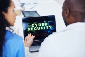 picture of a man and women in front of a laptop with the words Cyber Security on it